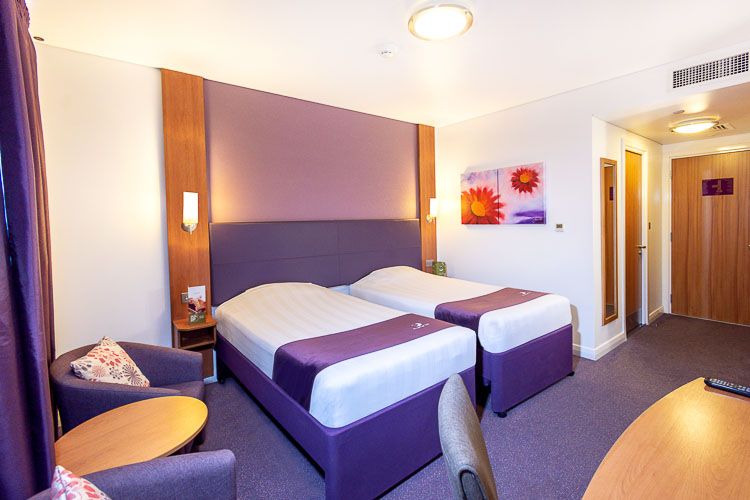 Twin bedroom with seating area and desk at Premier Inn Abu Dhabi International Airport hotel 
