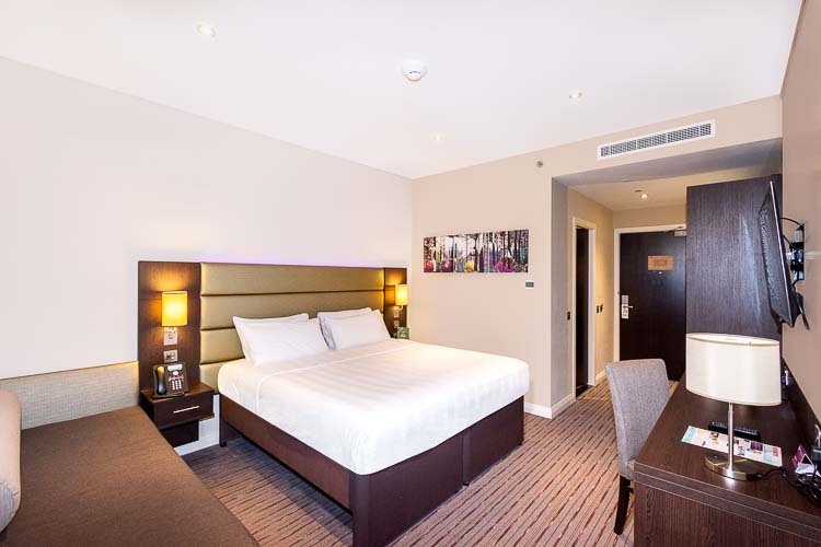Big double bed in hotel room in Dubai with sofa and desk in Premier Inn Dubai Al Jaddaf 