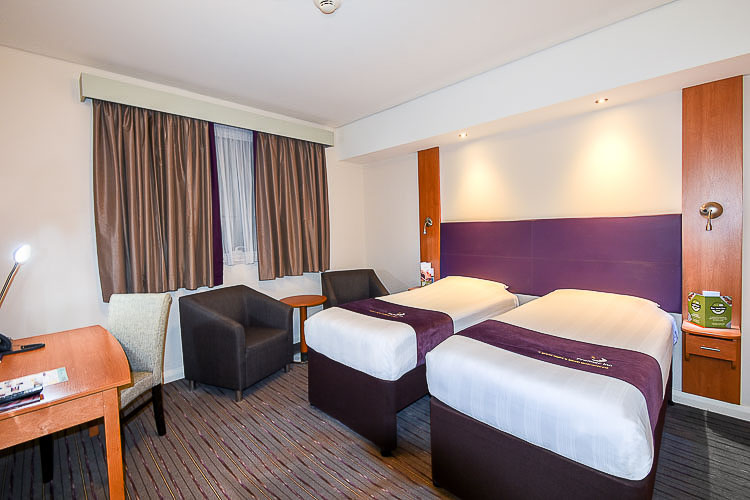 Twin room with two beds, a desk and seating area at Premier Inn Dubai International Airport