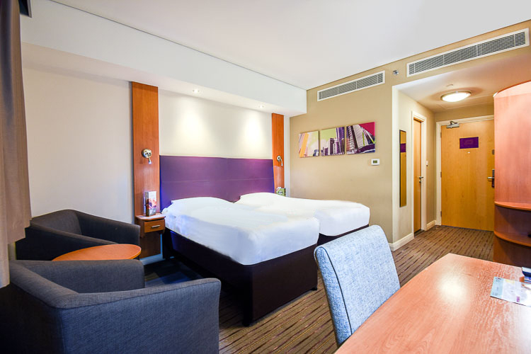 A twin room with two beds, en-suite bathroom and work space area at Premier Inn Dubai International Airport hotel