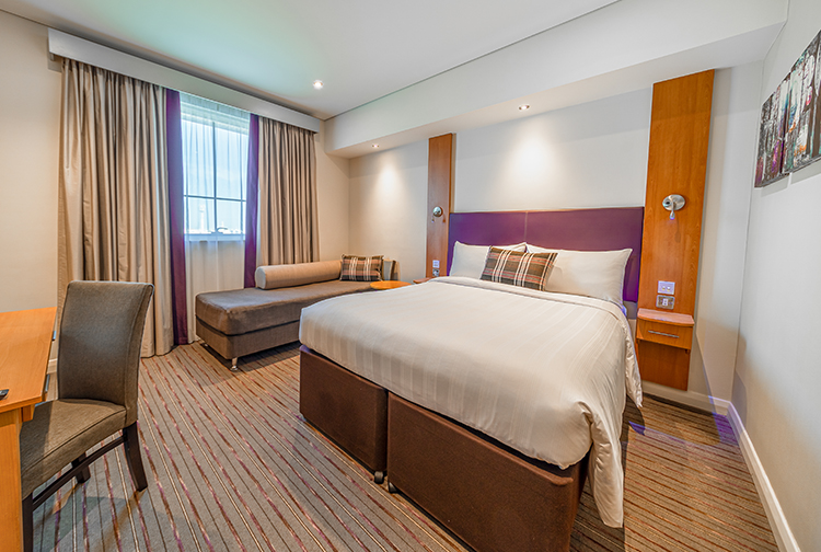 Double bedroom with sofa and ensuite bathroom in Premier Inn Dubai Investments Park hotel near Expo 2020