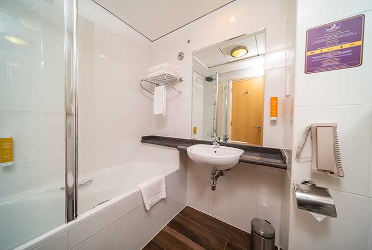 En-suite bathroom with bath and over-bath shower and glass shower screen.