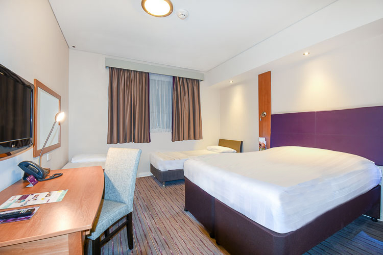 Family room at Premier Inn Dubai International airport with double bed and two single beds for children.