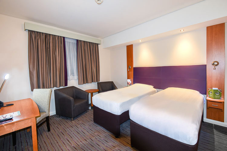 Twin bedroom with seating area and work desk in Silicon Oasis hotel