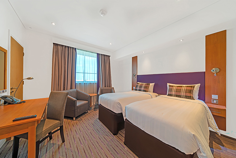 Twin beds with desk and seating area in hotel near Expo 2020 in Dubai Investments Park