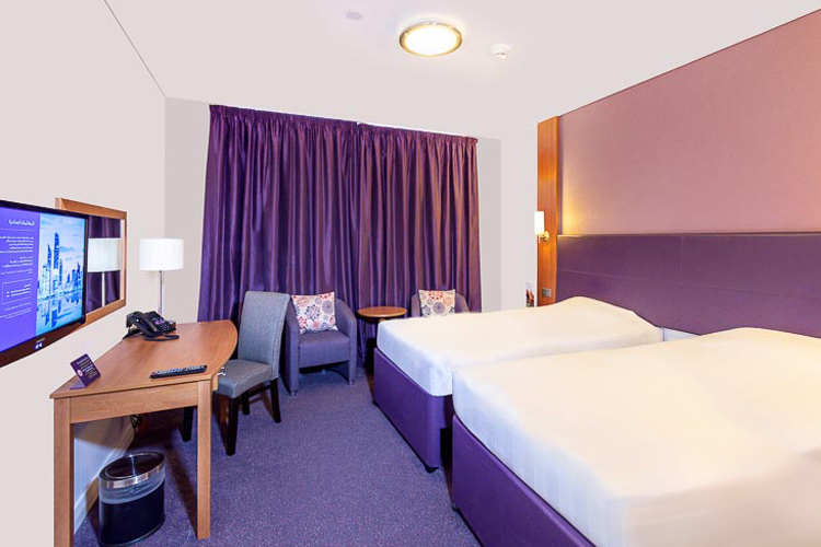 Twin room with two beds and desk area at Premier Inn Abu Dhabi International Airport hotel 